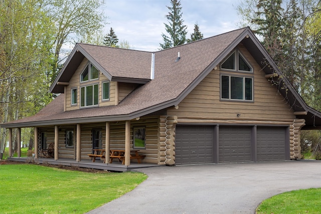 log-style house featuring covered porch, a front yard, and a garage