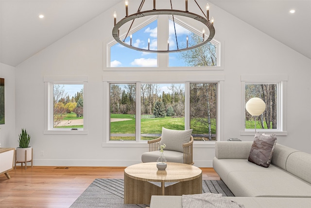 living room with a notable chandelier, light hardwood / wood-style flooring, and high vaulted ceiling