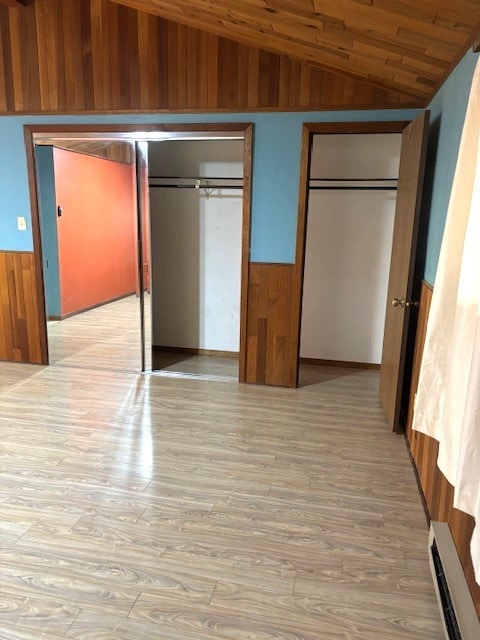 unfurnished bedroom featuring two closets, a baseboard radiator, light hardwood / wood-style flooring, lofted ceiling, and wood ceiling