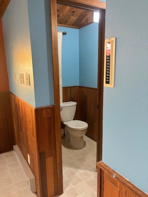 bathroom with wooden ceiling, toilet, and tile floors