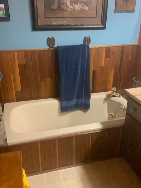 bathroom featuring tile flooring, vanity, and a bath to relax in