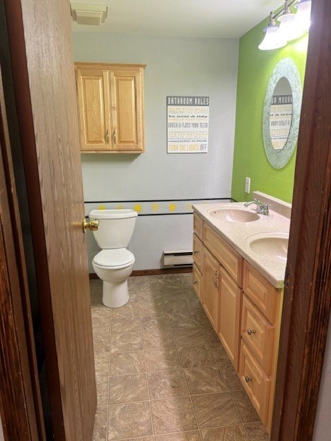 bathroom with tile floors, dual sinks, a baseboard heating unit, toilet, and oversized vanity