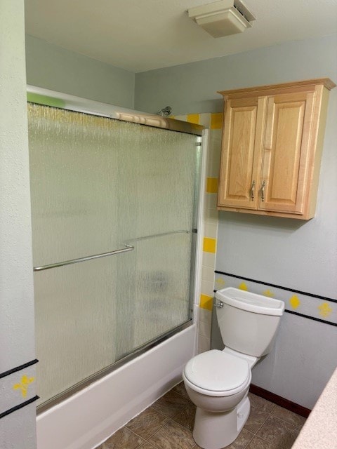 bathroom featuring enclosed tub / shower combo, toilet, and tile flooring