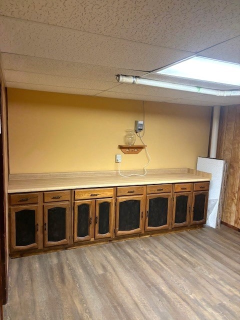 basement with a drop ceiling and wood-type flooring