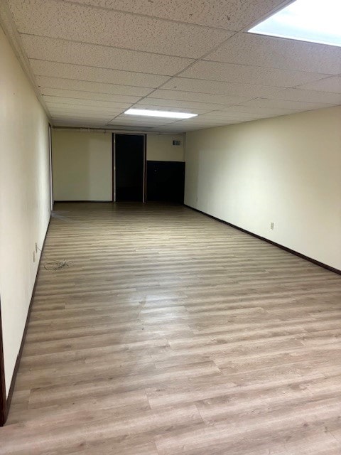 spare room with a paneled ceiling and light hardwood / wood-style floors