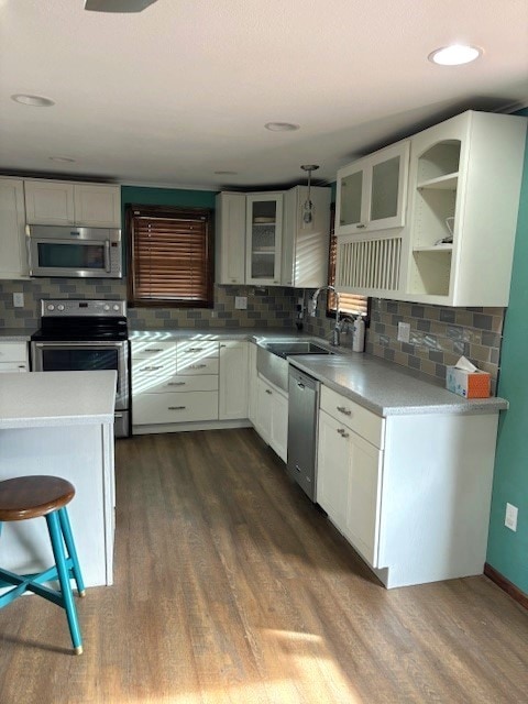 kitchen featuring dark hardwood / wood-style floors, backsplash, stainless steel appliances, and white cabinetry