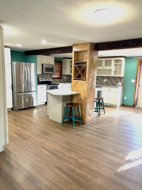 kitchen with a kitchen bar, white cabinets, appliances with stainless steel finishes, and light wood-type flooring