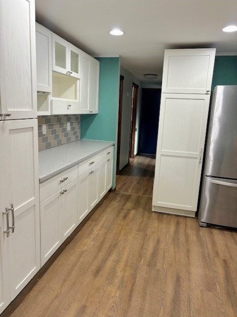 kitchen featuring backsplash, stainless steel fridge, white cabinetry, and hardwood / wood-style flooring