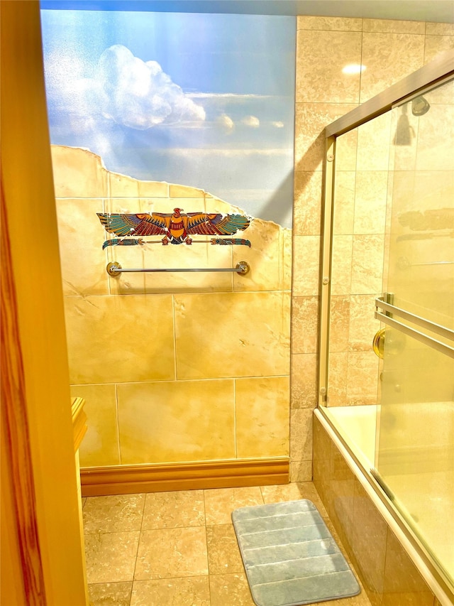 bathroom featuring tile flooring and bath / shower combo with glass door