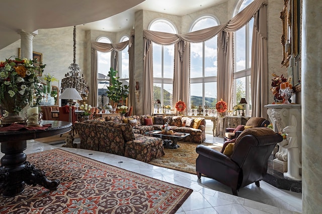 living room featuring decorative columns, a healthy amount of sunlight, light tile floors, and a towering ceiling