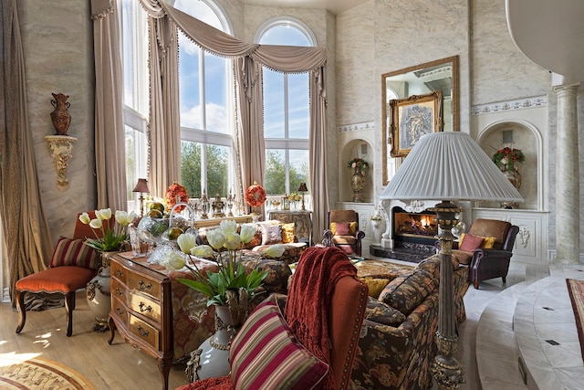 living room featuring a towering ceiling, light hardwood / wood-style flooring, and ornate columns