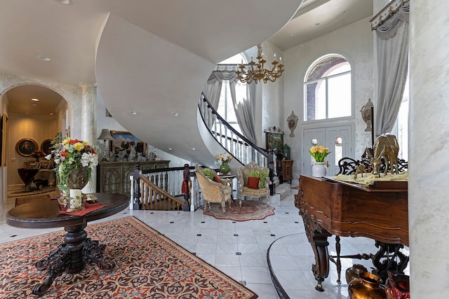 foyer with ornate columns, a chandelier, light tile floors, and a high ceiling