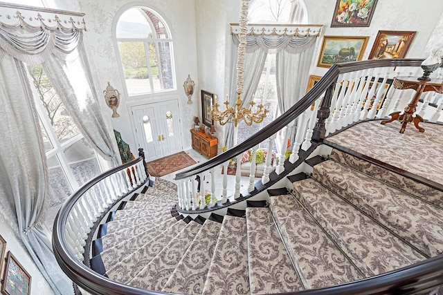 entryway with french doors, a towering ceiling, and an inviting chandelier