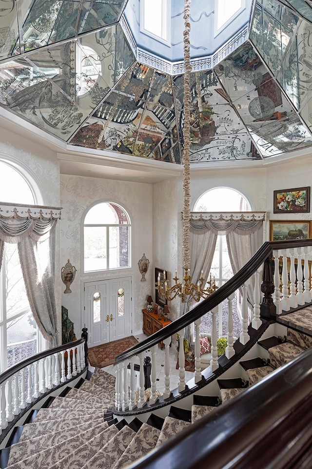 interior space with a towering ceiling, a wealth of natural light, ornamental molding, and french doors