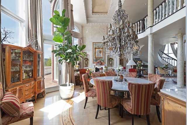 dining space featuring light wood-type flooring, ornate columns, a chandelier, and a high ceiling