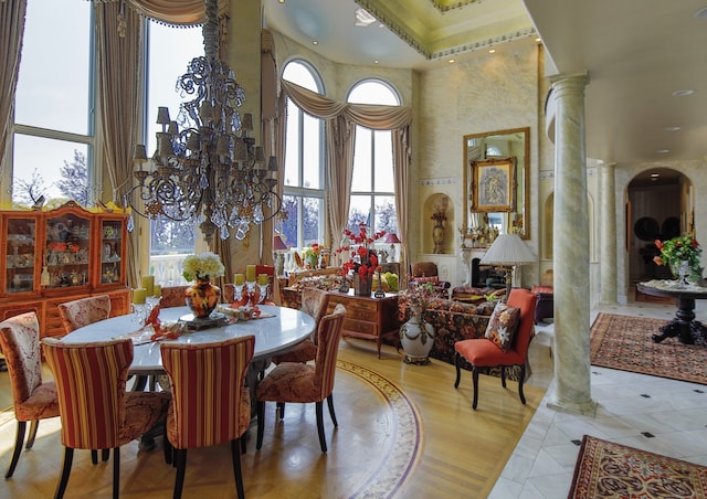 tiled dining space with a high ceiling, a chandelier, and decorative columns