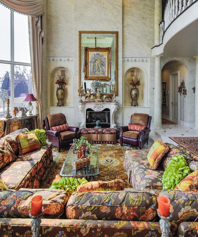 living room featuring tile floors, decorative columns, and a towering ceiling