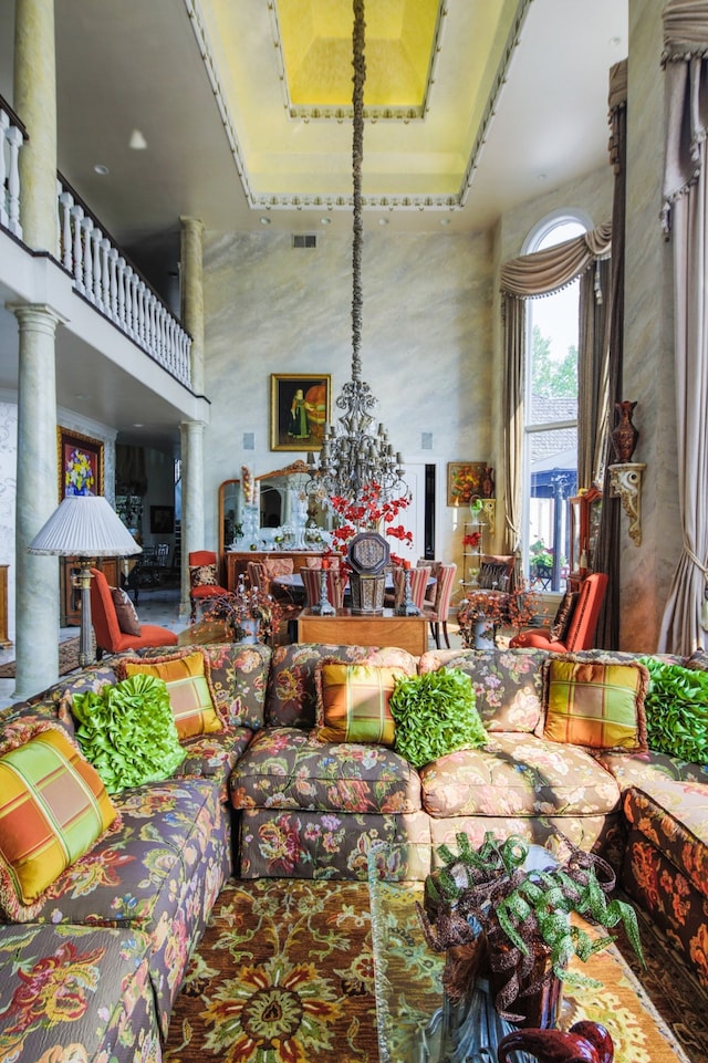 living room featuring a high ceiling, an inviting chandelier, and ornate columns