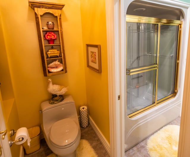 bathroom featuring enclosed tub / shower combo and toilet