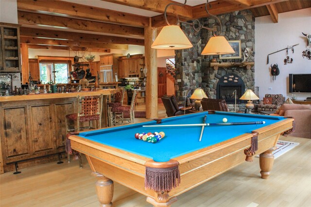 bar featuring beam ceiling, a stone fireplace, light wood-type flooring, and wine cooler