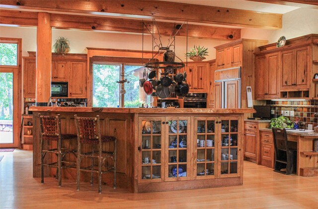 dining space featuring an inviting chandelier, beamed ceiling, and light wood-type flooring