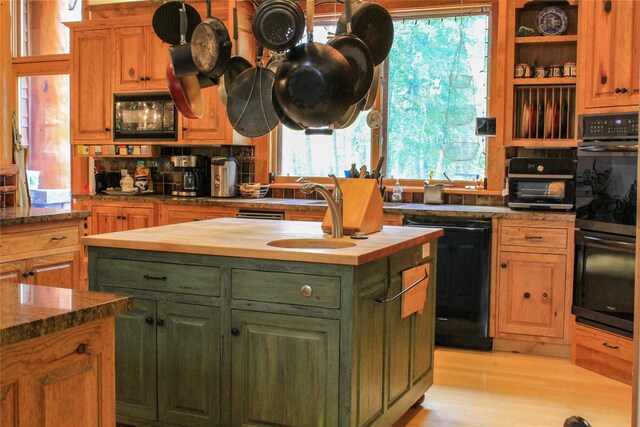 kitchen with light hardwood / wood-style flooring, a healthy amount of sunlight, black appliances, and a kitchen bar