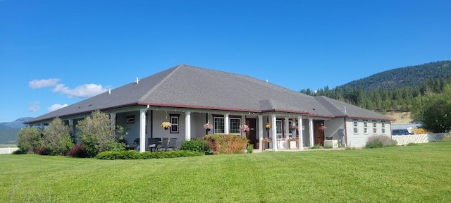 rear view of property featuring a lawn and a mountain view