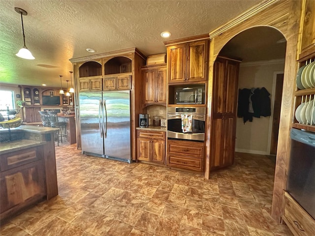 kitchen with crown molding, pendant lighting, stainless steel appliances, and a textured ceiling