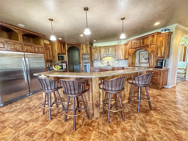 kitchen featuring backsplash, ornamental molding, sink, built in appliances, and decorative light fixtures