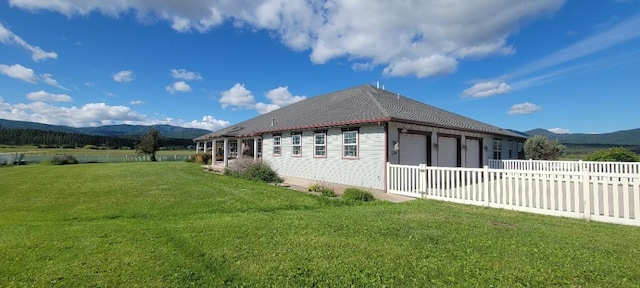 view of property exterior featuring a lawn, a mountain view, and a garage