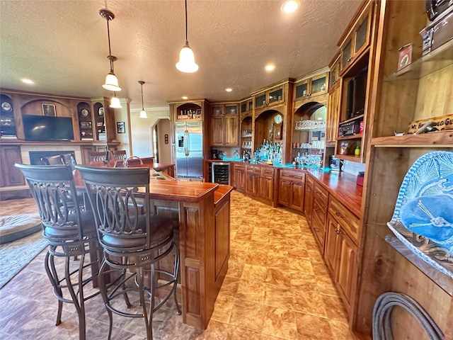 kitchen featuring pendant lighting, stainless steel refrigerator with ice dispenser, wine cooler, and a textured ceiling