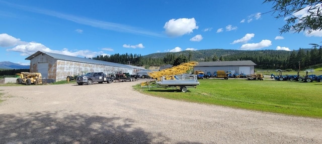 view of property's community with a mountain view, an outdoor structure, and a lawn