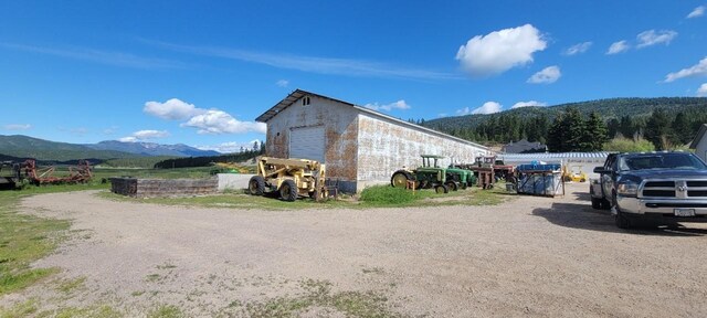 view of home's exterior with a mountain view, a garage, and an outbuilding