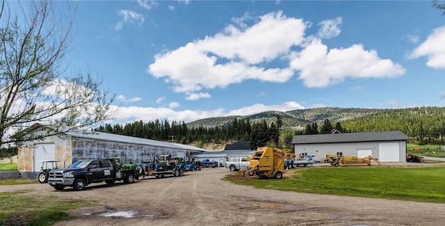 view of parking / parking lot featuring a lawn, a mountain view, and a garage