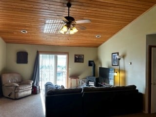 living room with ceiling fan, lofted ceiling, carpet floors, and wood ceiling