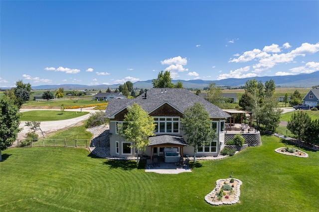 rear view of property featuring a lawn, a mountain view, and a patio area