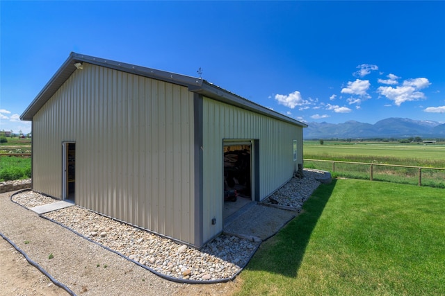 view of outbuilding featuring a mountain view, a rural view, and a yard