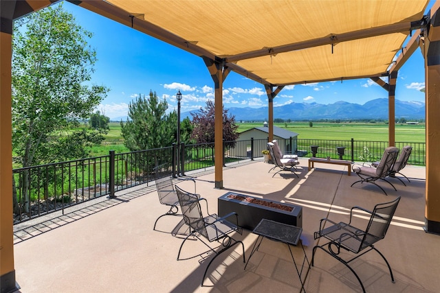 view of patio featuring a mountain view, a rural view, and a fire pit