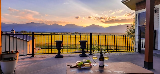 patio terrace at dusk featuring a mountain view and a balcony