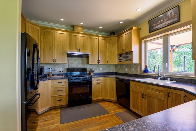 kitchen featuring decorative light fixtures, a kitchen bar, a kitchen island, black appliances, and light wood-type flooring