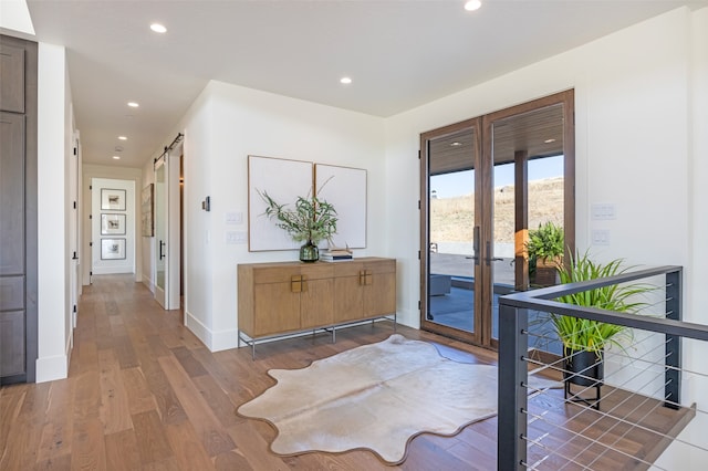 entrance foyer with a barn door, hardwood / wood-style flooring, and french doors