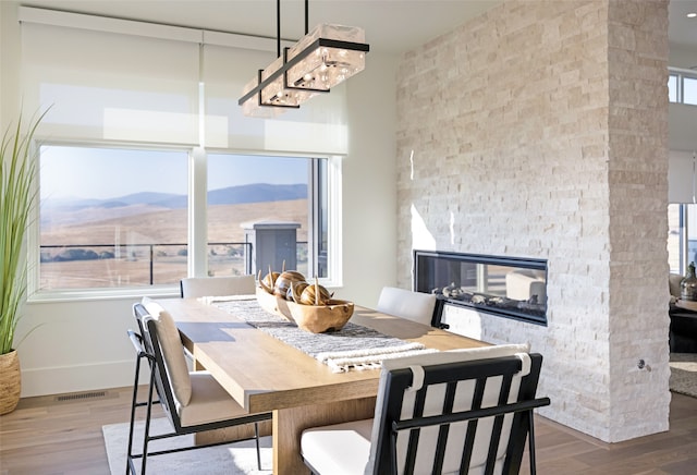 dining room featuring a mountain view, a stone fireplace, and wood-type flooring