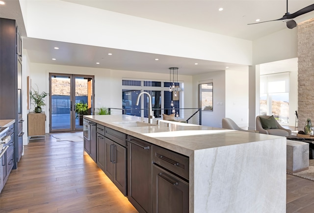 kitchen with a center island with sink, hanging light fixtures, sink, hardwood / wood-style flooring, and ceiling fan