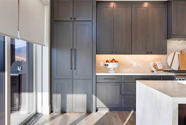 kitchen with backsplash, stainless steel stove, and light wood-type flooring