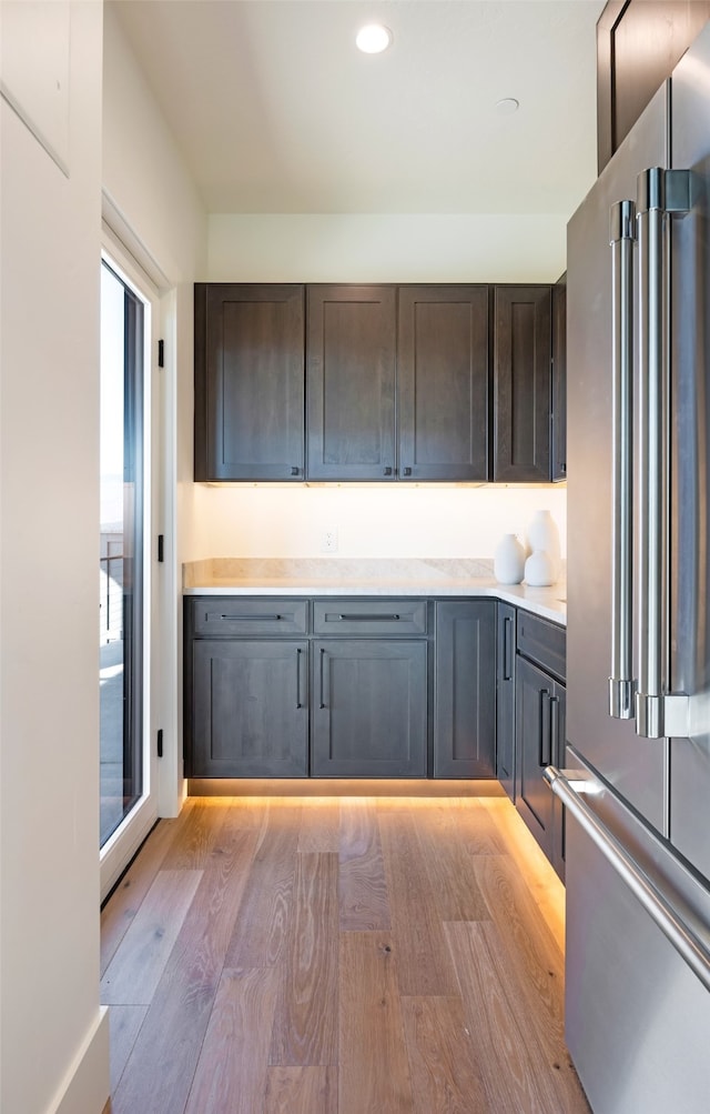 kitchen featuring high end fridge, light wood-type flooring, and dark brown cabinets