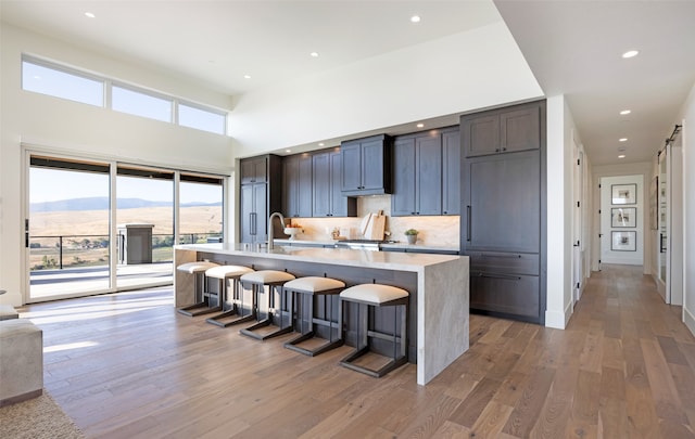 kitchen with dark wood-type flooring, a mountain view, a breakfast bar, and a kitchen island with sink