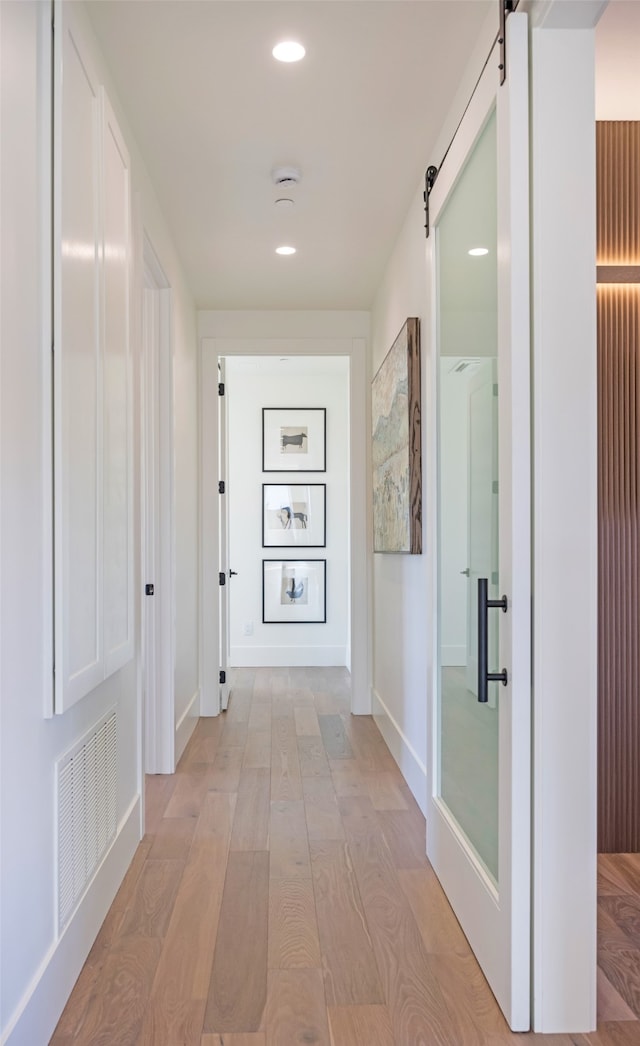 hall featuring a barn door and light hardwood / wood-style floors