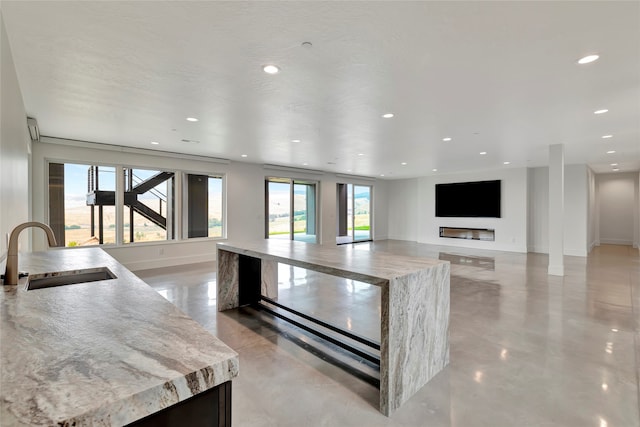 kitchen featuring a fireplace, a center island, light stone counters, and sink