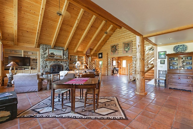 dining room with beam ceiling, a stone fireplace, and dark tile floors