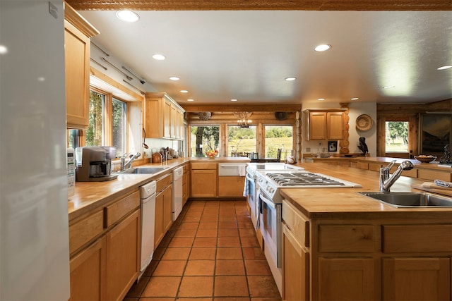 kitchen with white appliances, sink, a healthy amount of sunlight, and butcher block countertops